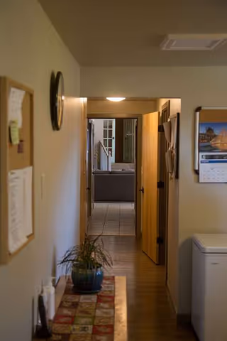 Narrow hallway in Canyon Creek AFH with open doors leading to a living area.