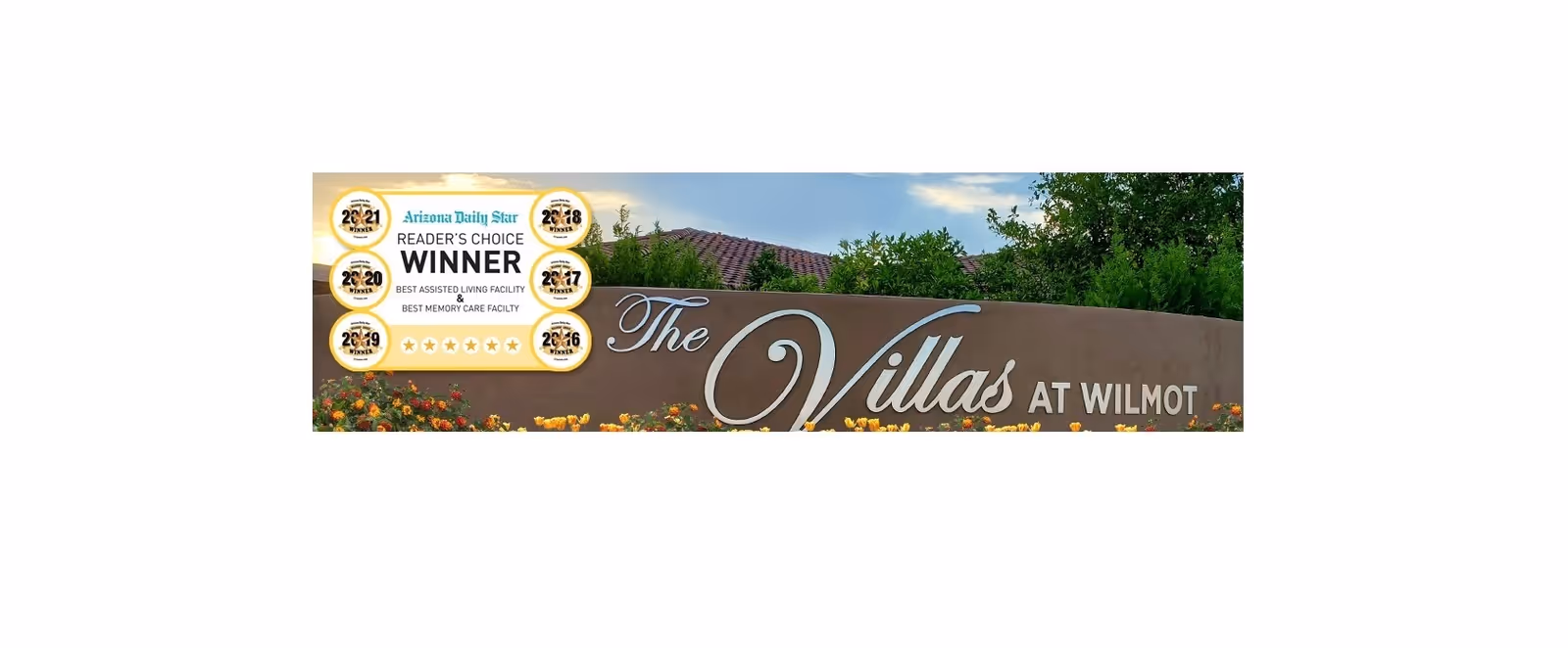 Outdoor sign for The Villas at Wilmot with flowers in front and trees behind. The sign also displays multiple Arizona Daily Star Reader's Choice Winner badges from 2016 to 2021 for Best Assisted Living Facility and Best Memory Care Facility.