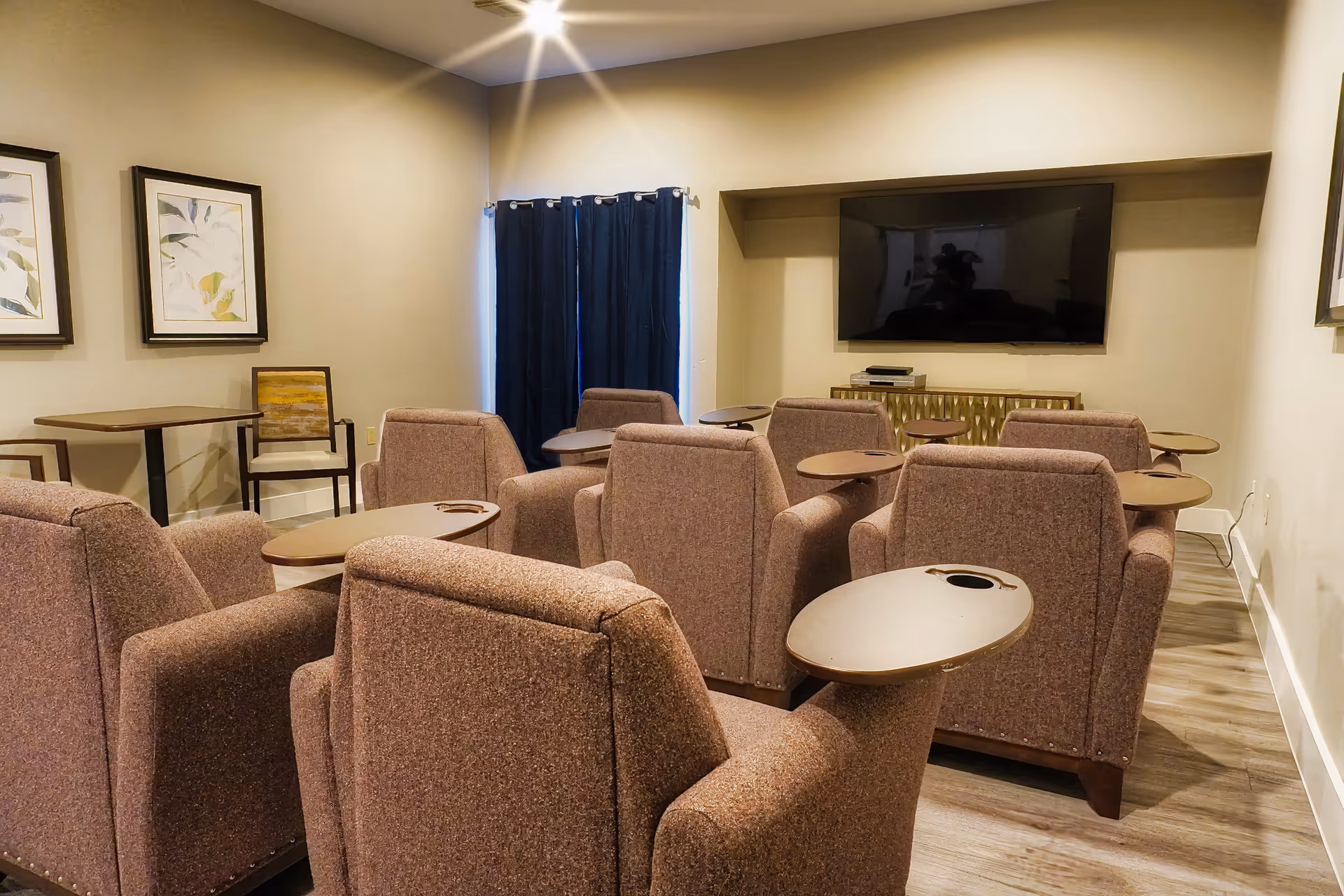 Small media room with several brown recliners arranged facing a wall-mounted flat-screen television.