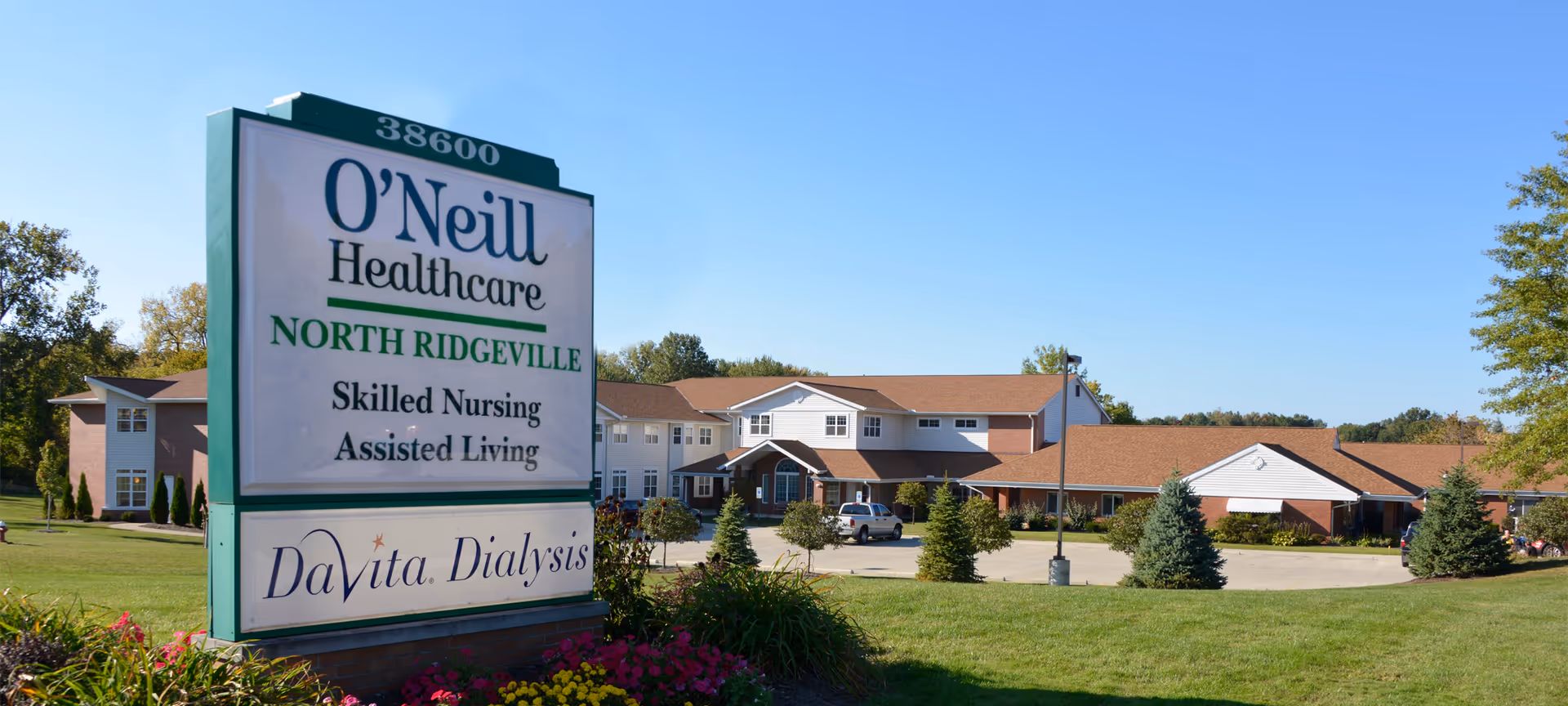 Sign reading "O'Neill Healthcare North Ridgeville" with the skilled nursing facility and landscaped grounds in the background.