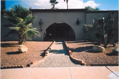 Exterior view of Aslan Adult Care Home with desert landscaping and an arched entrance.