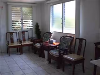 A small indoor lounge with wooden chairs along the wall by bright windows.