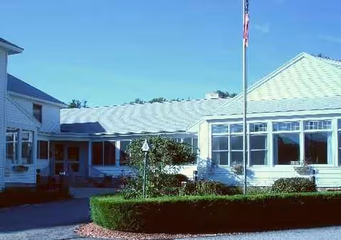 Front exterior view of Bel-Air Nursing Home with hedges, flagpole, and large windows