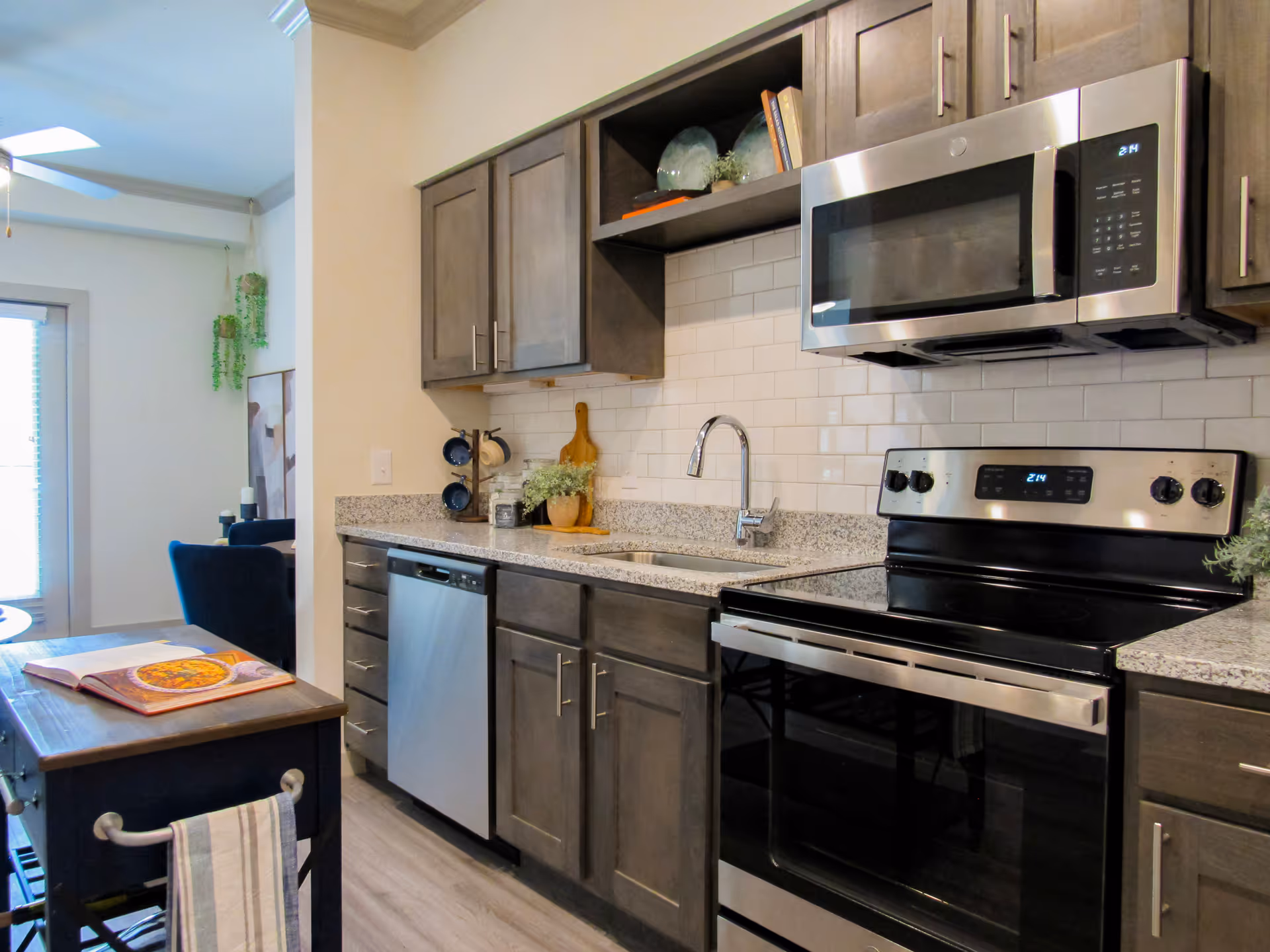Modern kitchen with stainless steel range, over-the-range microwave, dishwasher, gray cabinets and granite countertops.