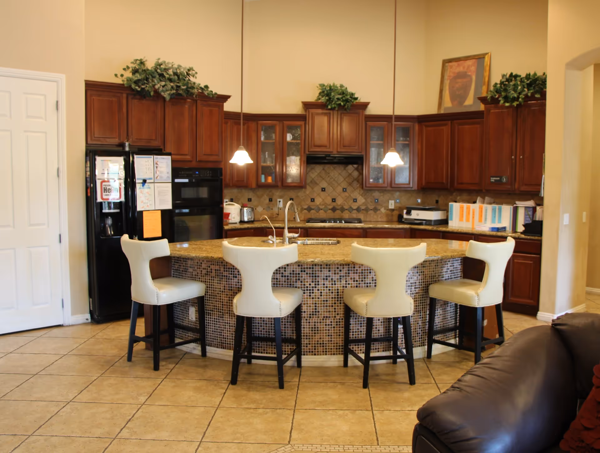 Open-concept kitchen with dark wood cabinets, tiled island, and white bar stools.