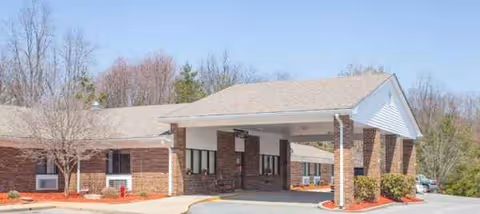 Single-story brick senior living facility with a covered entrance and parking in front.