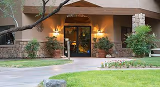 Front entrance of Rustic Ranch Senior Living with warm lights and landscaping