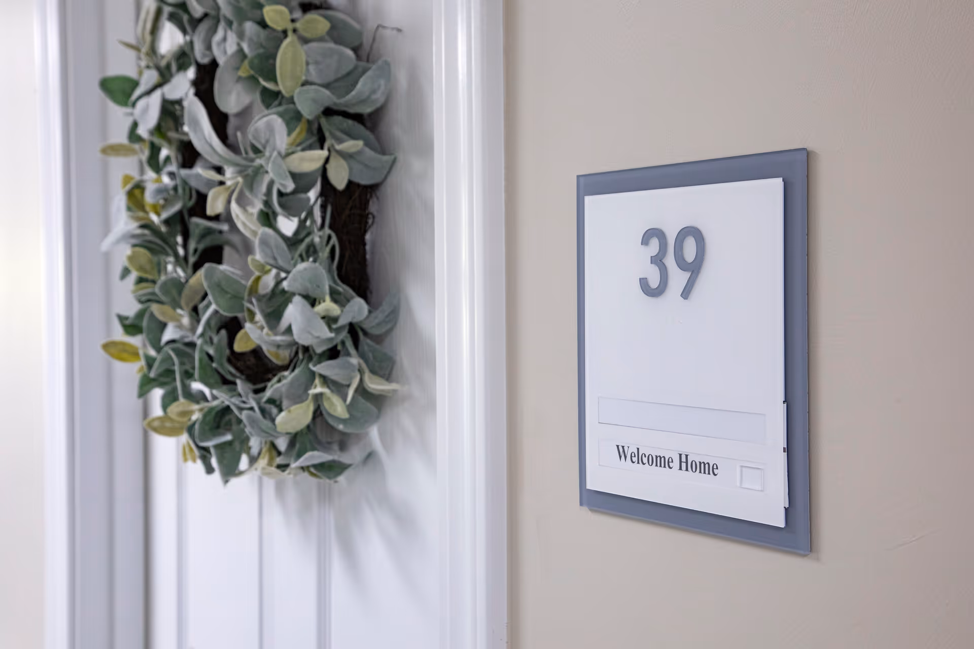 Door adorned with a leafy wreath and a room number sign reading "39" with "Welcome Home" on the wall.