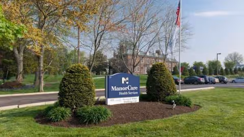 Exterior view of a nursing facility with a landscaped entrance sign.