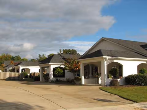 Facade of Amberley Senior Community with white arches and manicured landscaping.