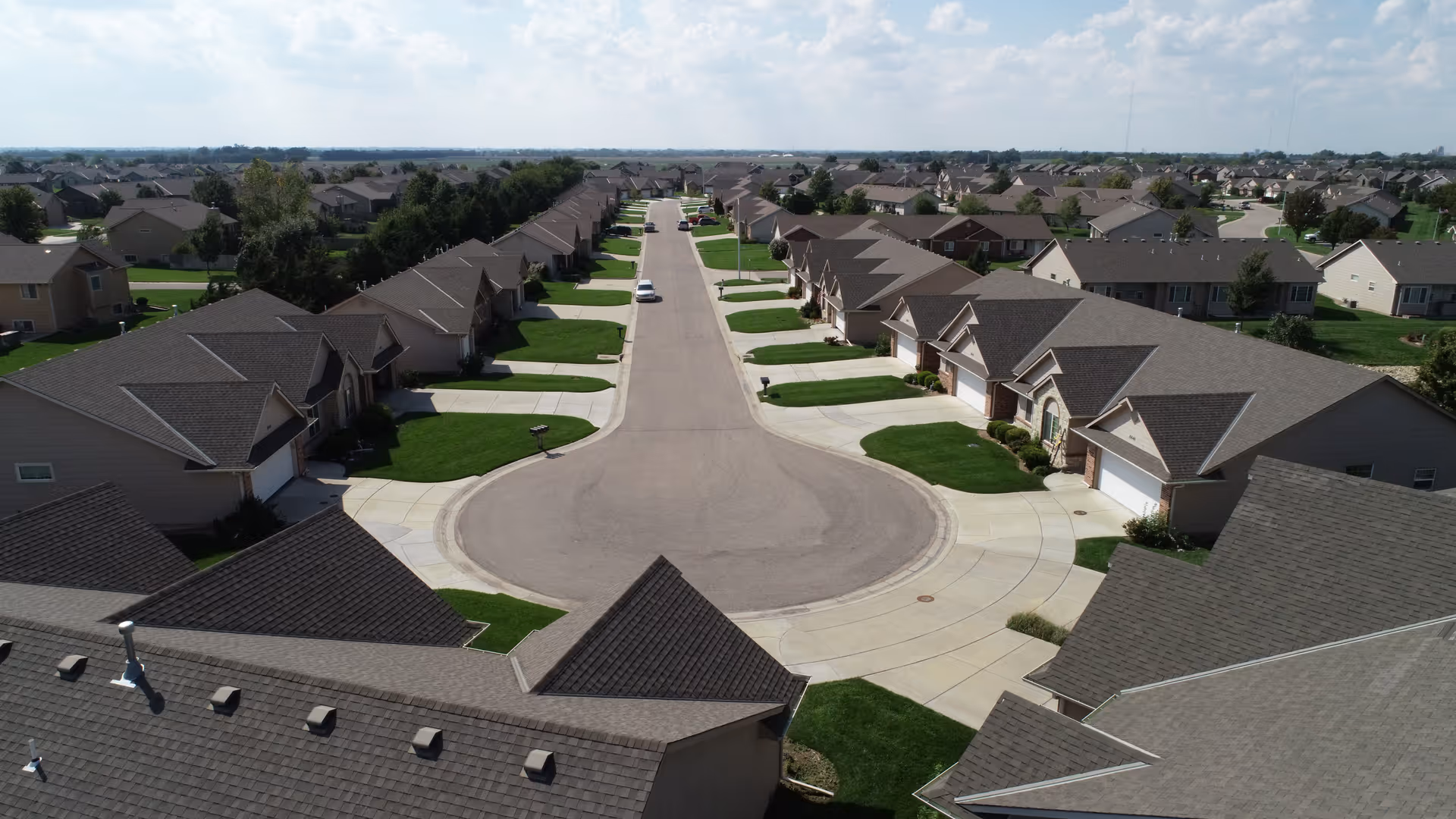 Aerial view of a cul-de-sac lined with similar single-story homes and driveways in a suburban neighborhood.