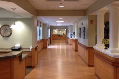Interior corridor in a senior living facility with a reception desk at the far end