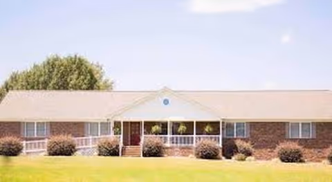 Front view of a brick senior living facility with entryway and shrubs.
