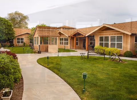 Exterior view of Wildflower Lodge Senior Living with curved walkway and green lawn.