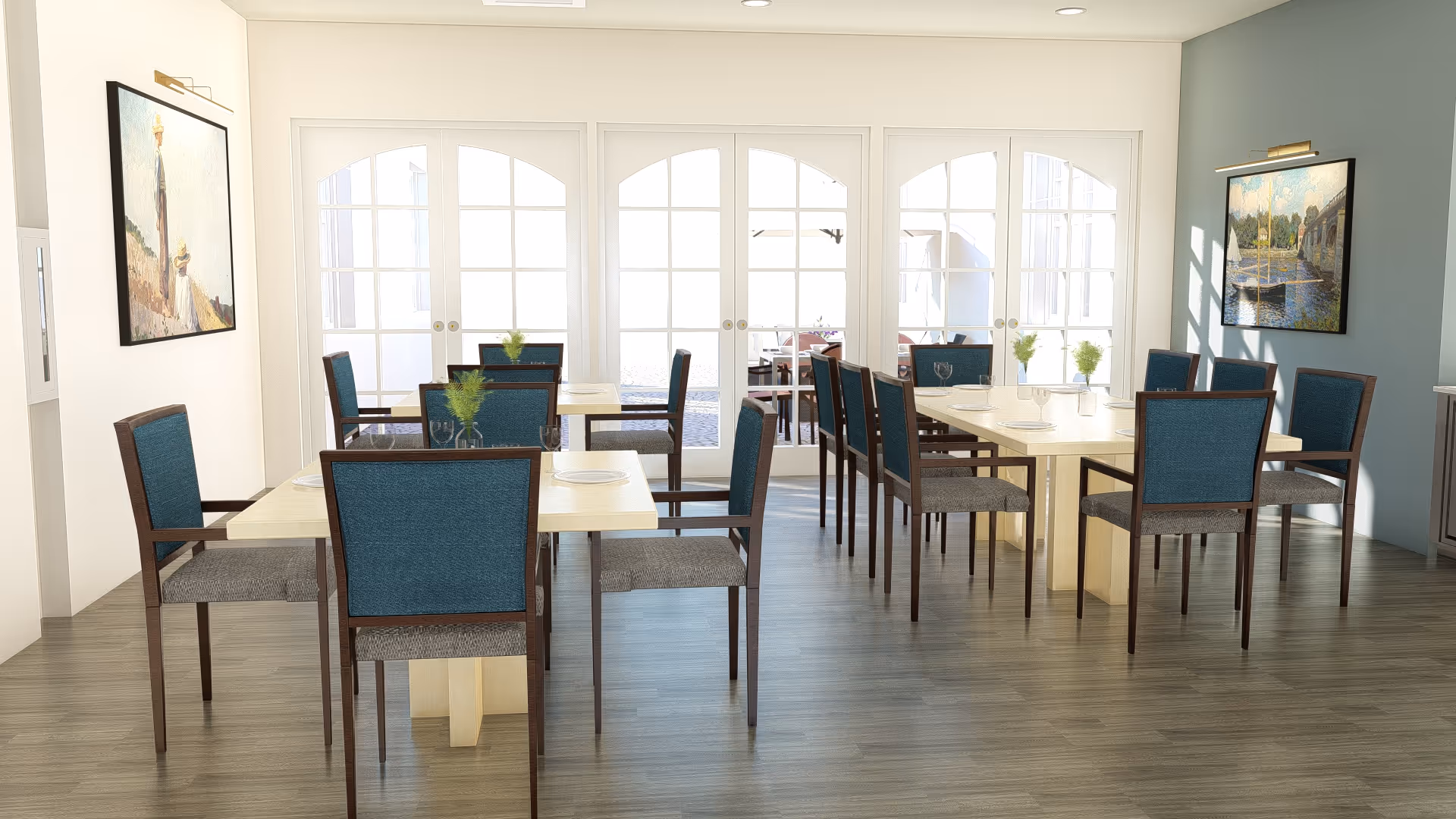 A bright dining room with multiple light wood tables and blue cushioned chairs arranged neatly. The room has large white-framed glass doors letting in natural light. Two paintings hang on the walls, and small green plants are placed on the tables.