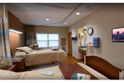 A senior living bedroom with a bed, nightstands, window, and doorway.