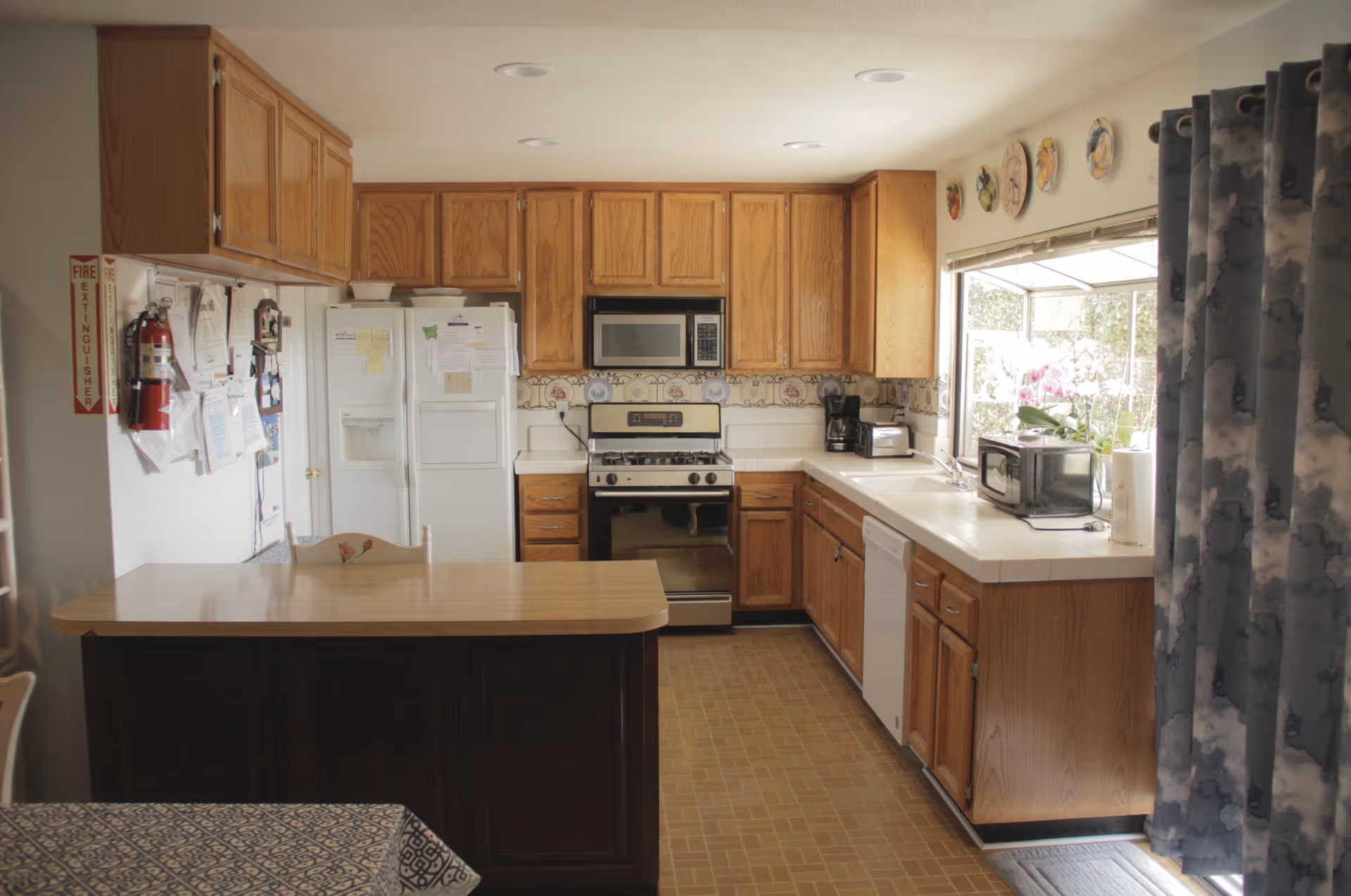 Bright kitchen with oak cabinets, a central island, white refrigerator and stove, and a window over the sink.