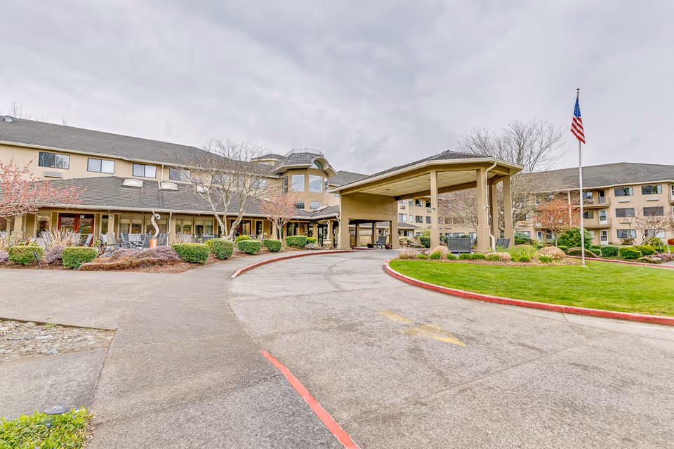 Exterior view of Solstice Senior Living at Bellingham with entrance canopy and American flag