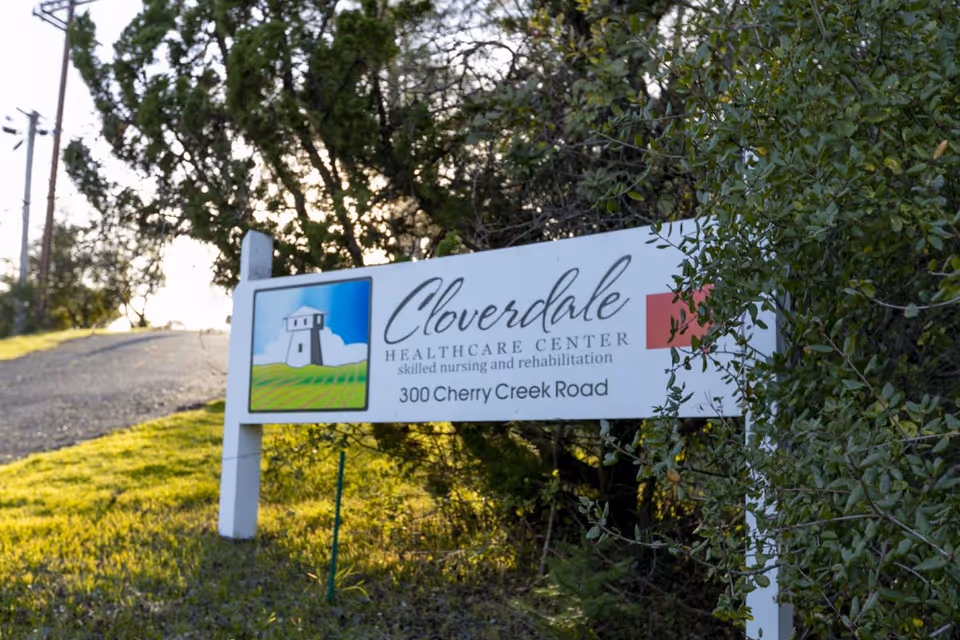 A roadside sign reading 'Cloverdale Healthcare Center, 300 Cherry Creek Road' set in grass with trees behind it.