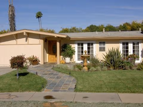 Villa Blanca senior living facility front exterior with curved path, fountain, and manicured lawn.