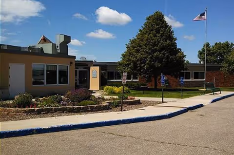 Front exterior of Faulkton Senior Living with entrance, landscaping, and American flag.