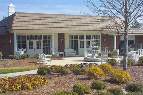 Front view of Life Care Center of Cleveland with entrance, chairs, and fountain.