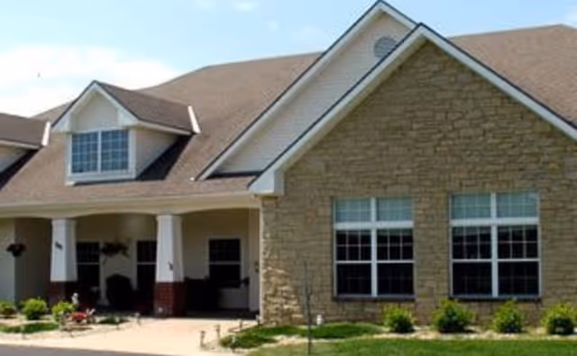 Front exterior of Commodore Park Plaza senior living facility with stone facade and covered entry.