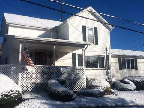 Exterior of Reward Senior Care of Lisbon, a white two-story building with a snow-covered front porch.