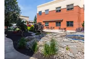 Exterior view of a Spring Creek senior living building with a stone courtyard and landscaping.
