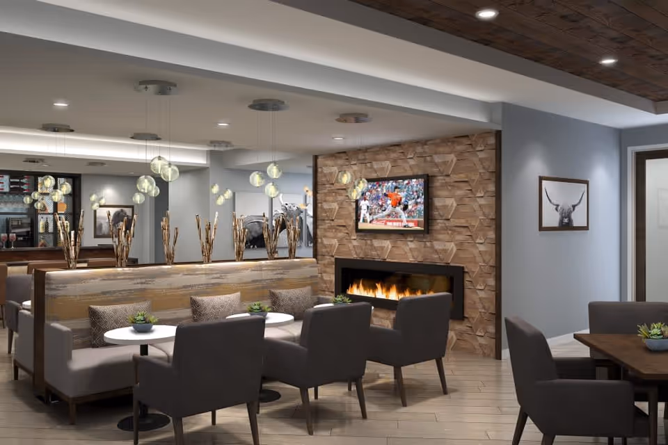 Modern communal dining and lounge area with booths, tables, armchairs, a fireplace and wall-mounted TV.