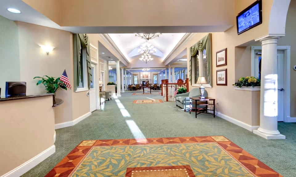 Spacious carpeted lobby with chandeliers, seating areas, a reception desk and decorative columns.
