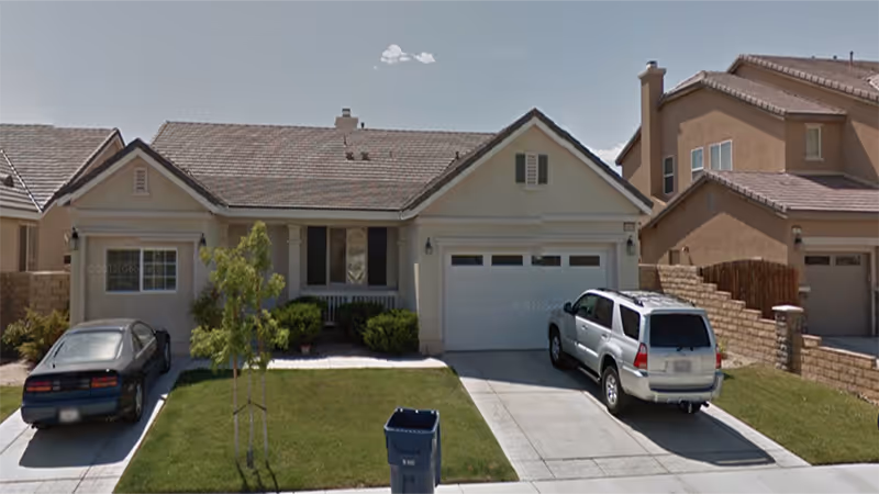Front view of a beige, single-story house with two garages and parked cars.
