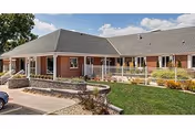 Exterior view of a single-story brick senior care facility with a covered entrance.