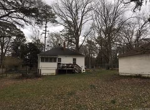 Small white building with a wooden deck in a leaf-strewn yard.