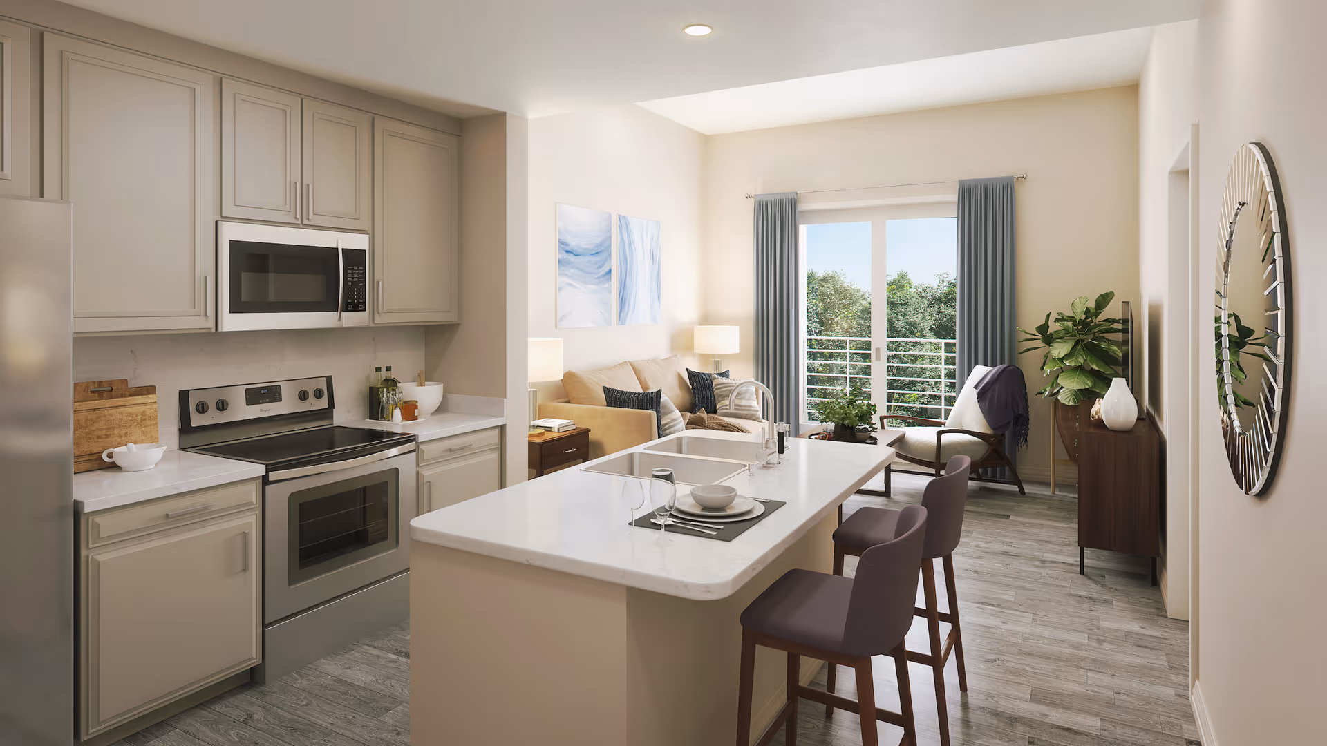 A modern open-concept apartment interior featuring a kitchen with beige cabinets, stainless steel appliances including a microwave and stove, and a white marble island with two purple chairs. The living area has a beige sofa, a wooden side table with a lamp, a chair, a large plant, and a round mirror on the wall. Large windows with blue curtains provide natural light and a view of greenery outside.