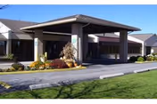 Entrance of a senior care facility with a covered drop-off and landscaped grounds.
