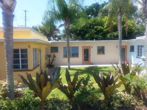 Colorful single-story senior living facility with a sunlit courtyard and palm trees.