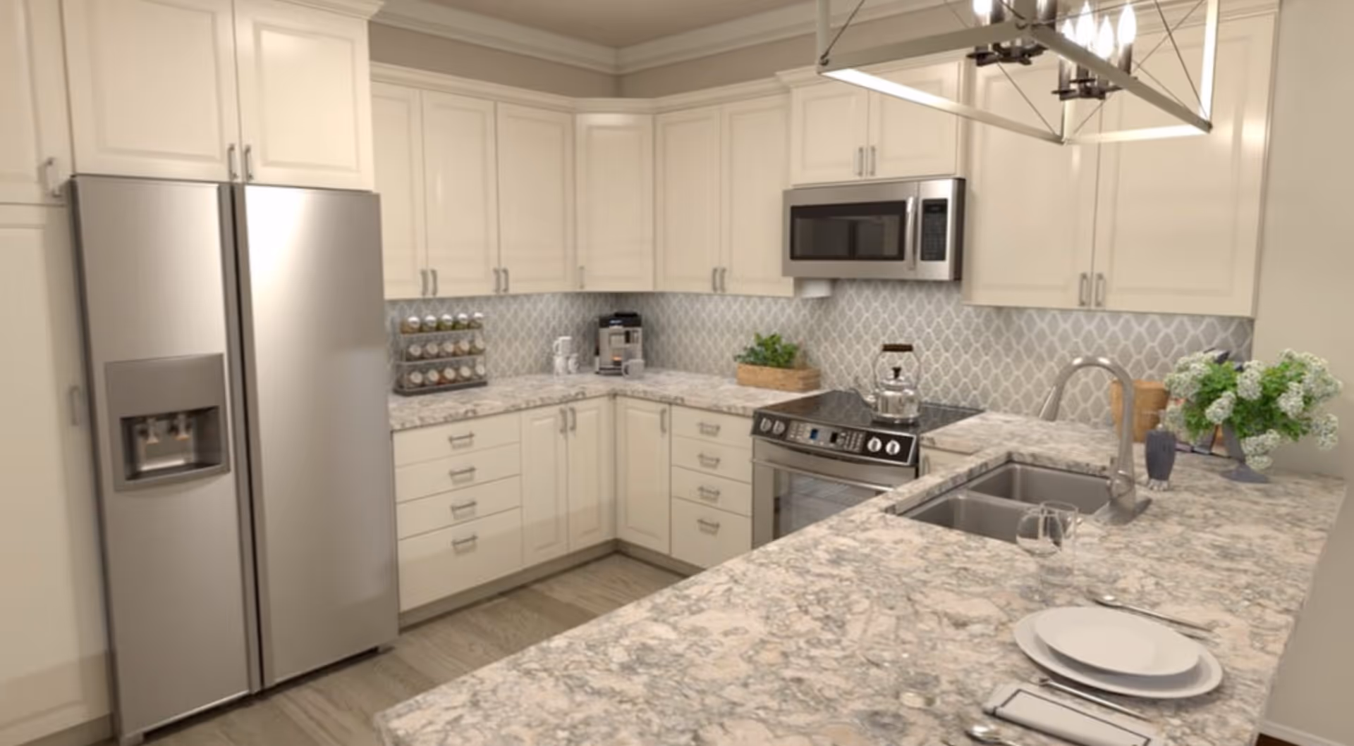 Bright modern kitchen with marble countertops, white cabinetry, stainless steel refrigerator, stove and microwave, and an island sink under a pendant light.