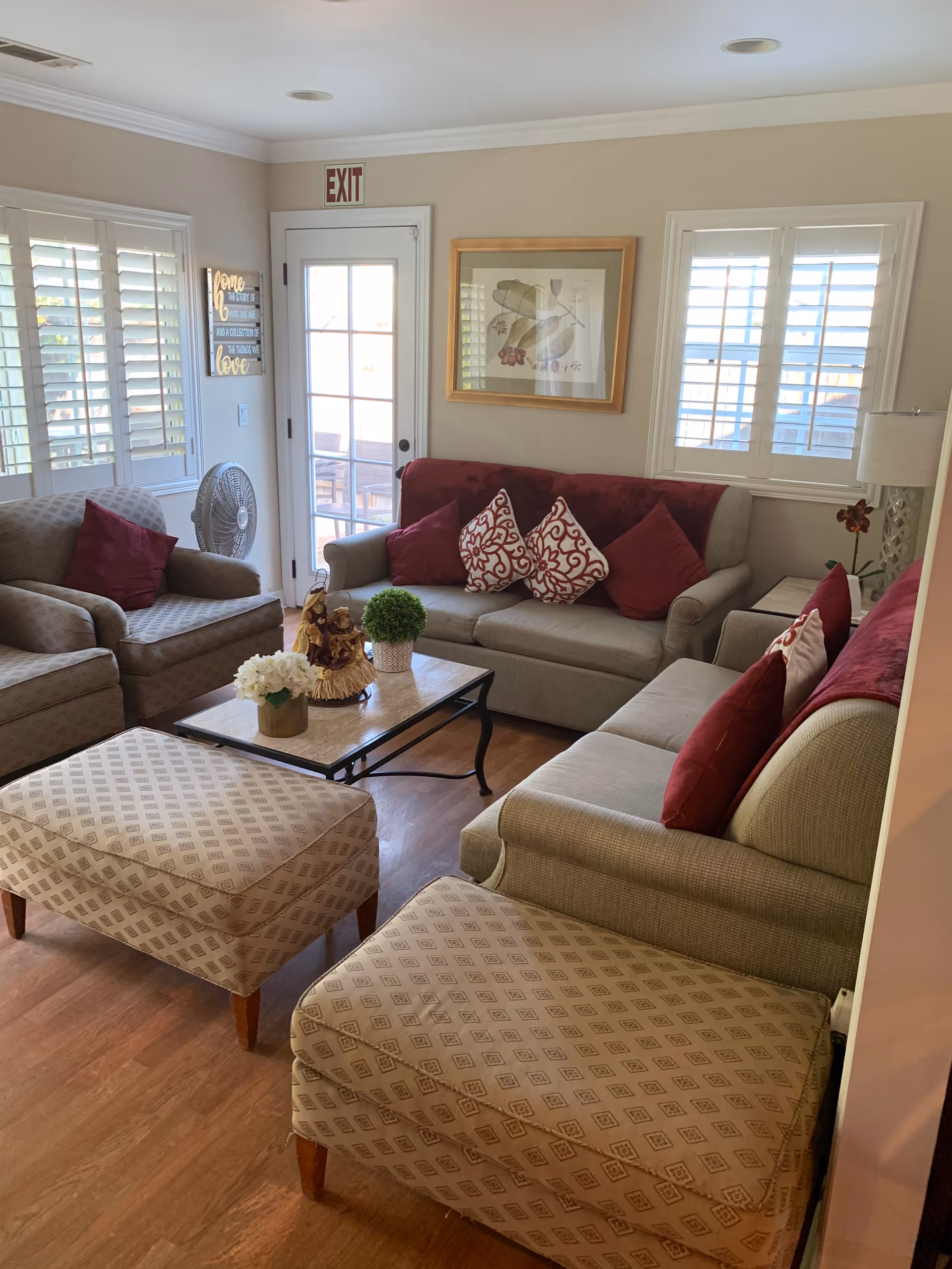 Cozy living room with multiple sofas and armchairs, patterned ottomans, a coffee table with decorations, and red accent pillows.