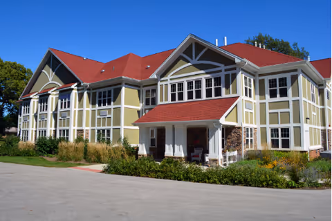 Exterior view of a multi-wing senior living facility with red roof and landscaped grounds.