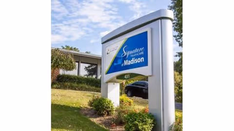 Sign for Signature HealthCARE of Madison at the facility entrance with landscaping and a building in the background.