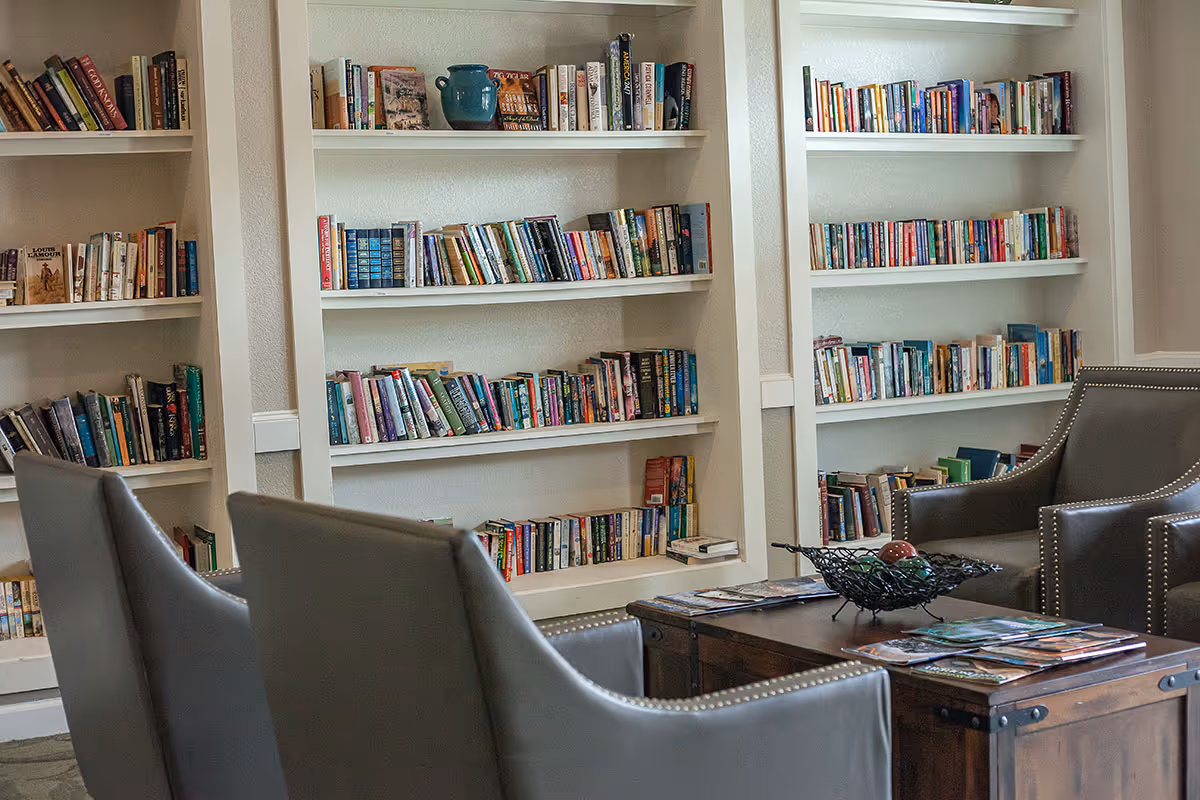 Cozy seating area with built-in bookshelves filled with books, leather chairs, and a wooden coffee table.