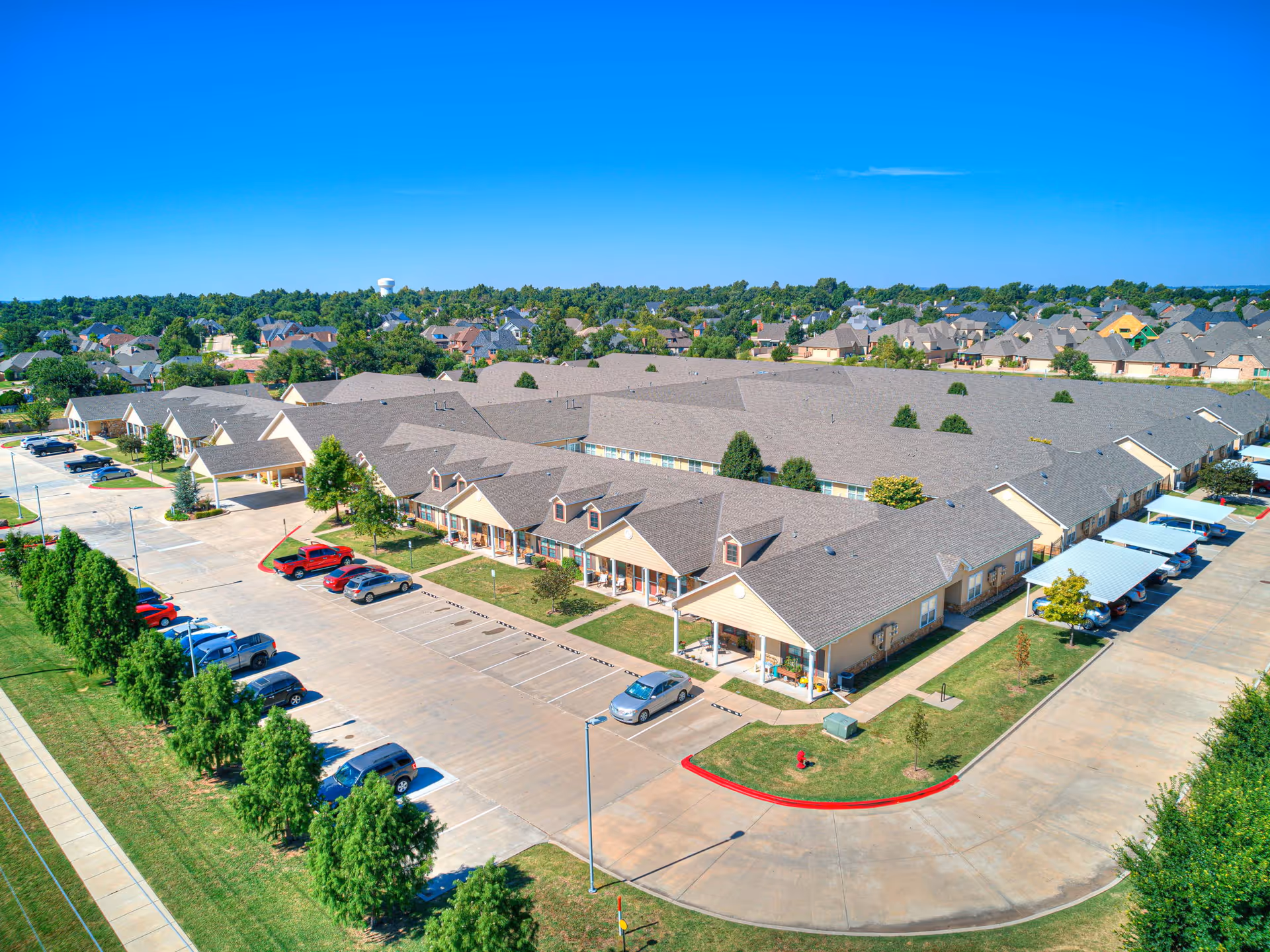Aerial view of a senior living campus with beige buildings, parking lots, and landscaped grounds.