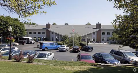 Front exterior view of Laurel Oaks Senior Living building with parked cars in front.