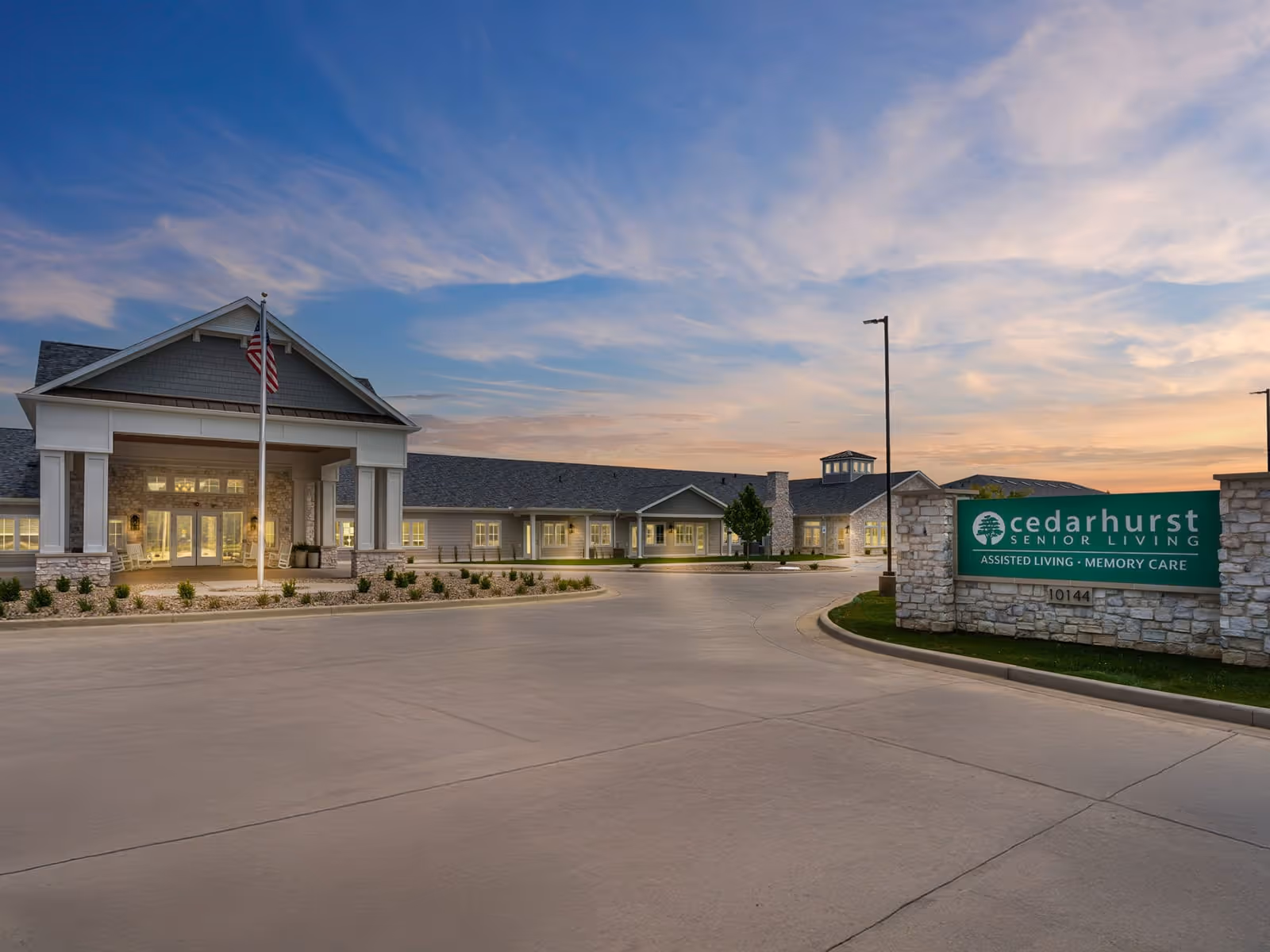 Front exterior of the Cedarhurst Senior Living building and entrance with a landscaped driveway and signage at dusk.