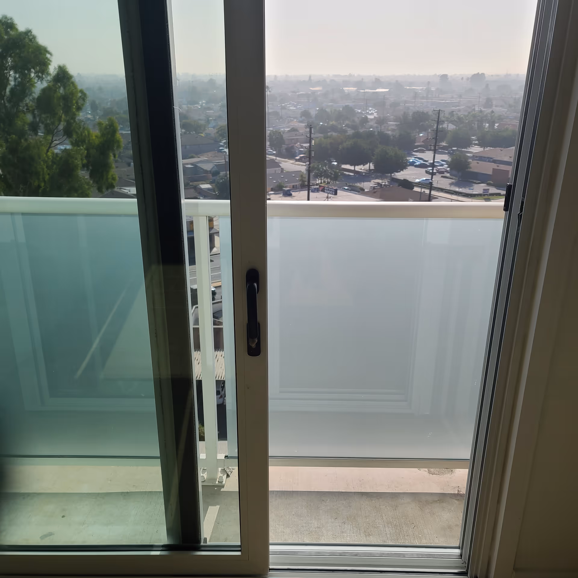 A view from an open balcony door looking out over a residential area.