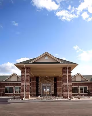 Front view of a brick senior living facility entrance under a covered porte-cochère.