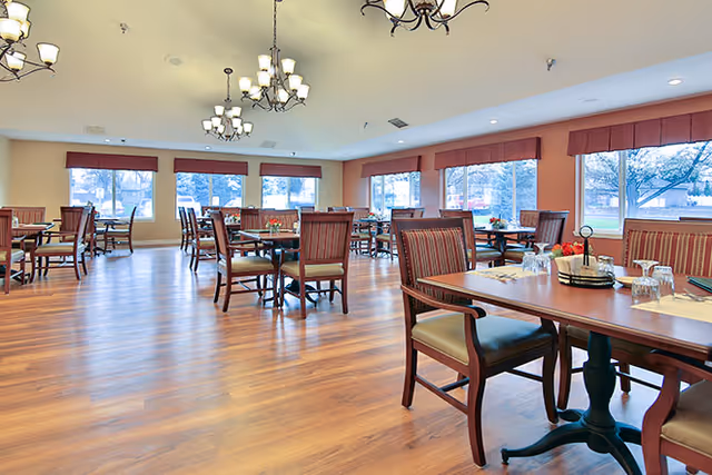 Bright, spacious dining room with wooden tables and chairs, large windows, and chandeliers.