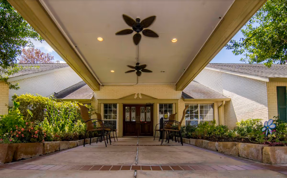 Front entrance of Tomball Retirement Center with a covered walkway and outdoor seating.