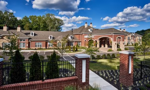 Waltonwood Cotswold exterior featuring a brick building, arched entrance, and manicured grounds.